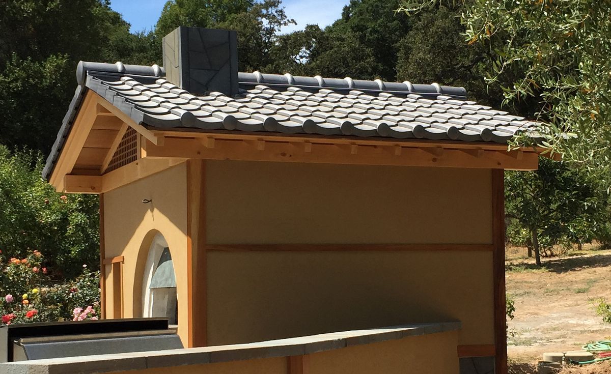 A roof with a vent on it and a building in the background.