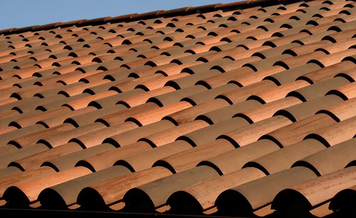 A roof with a vent on it and a building in the background.
