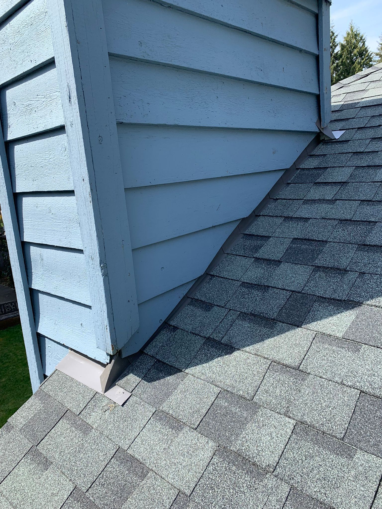 A blue house with a gray roof and a chimney on the side.