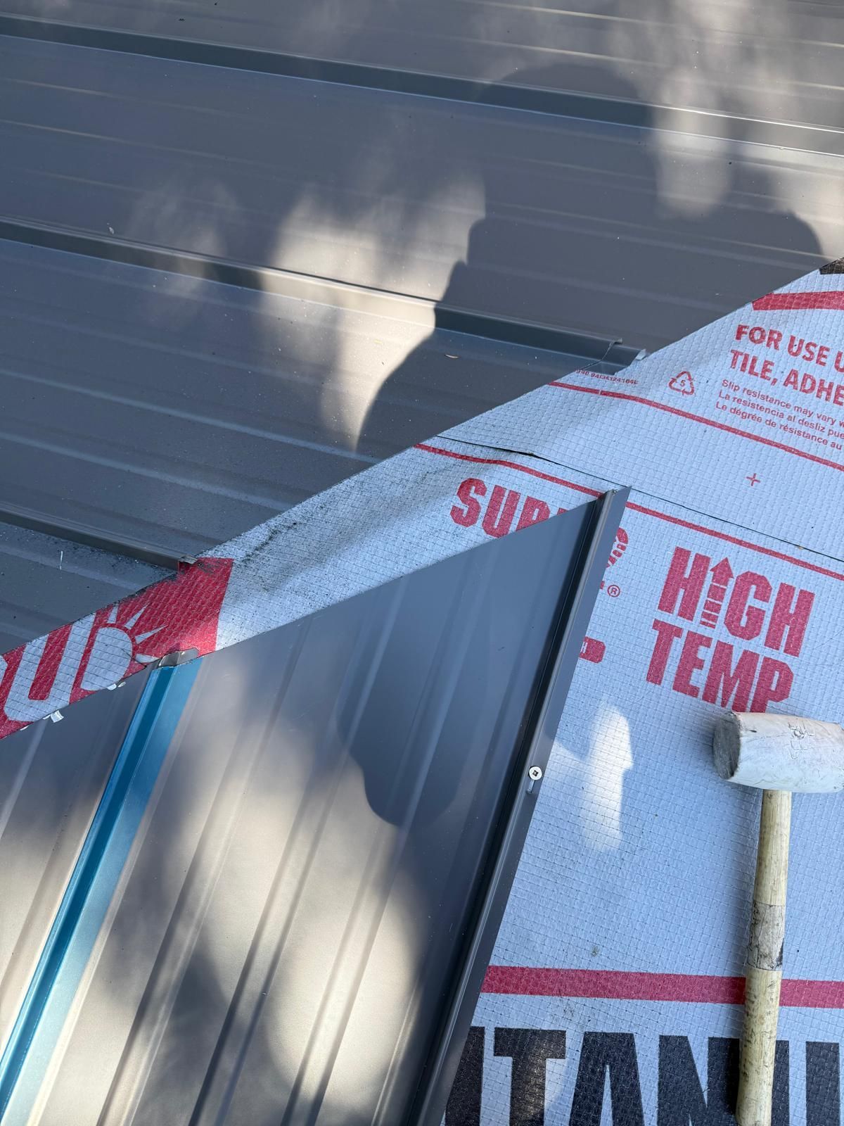 Raised seam metal panels beside printed high temperature underlayment and a mallet