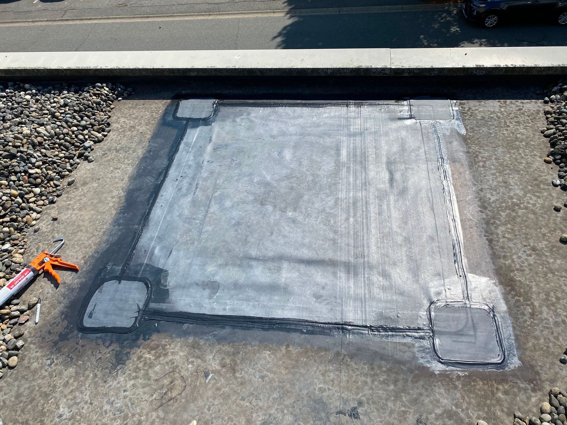 Rectangular membrane patch beside a gravel surfaced roof area