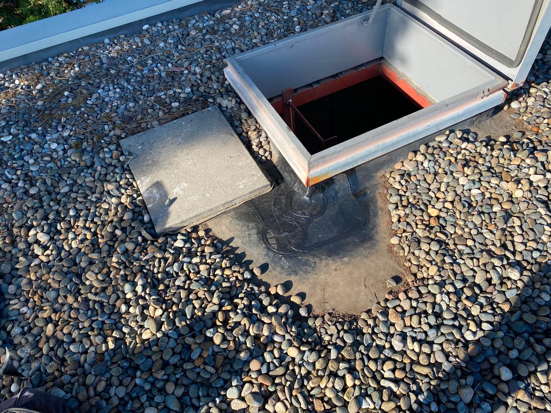 Open roof access hatch with flashing surrounded by gravel