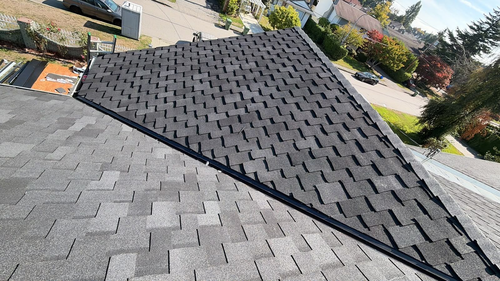 Grey shingle roof planes meeting at a metal valley