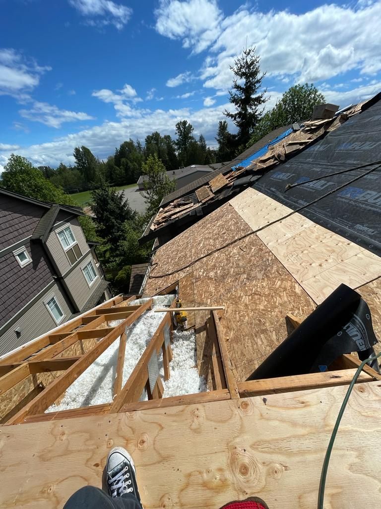 A person is laying on the roof of a house under construction.
