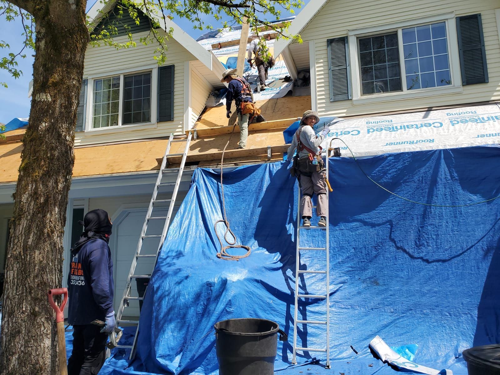A group of people are working on the roof of a house.