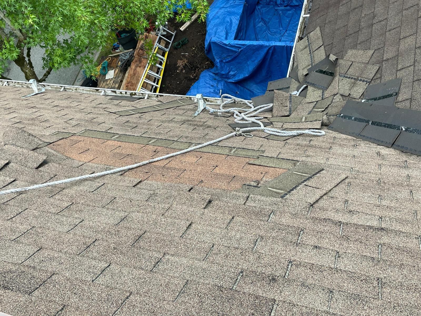 Damaged roof with missing shingles. Tarpaulin covering a large hole.