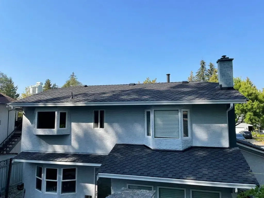A large white house with a black roof and a chimney.
