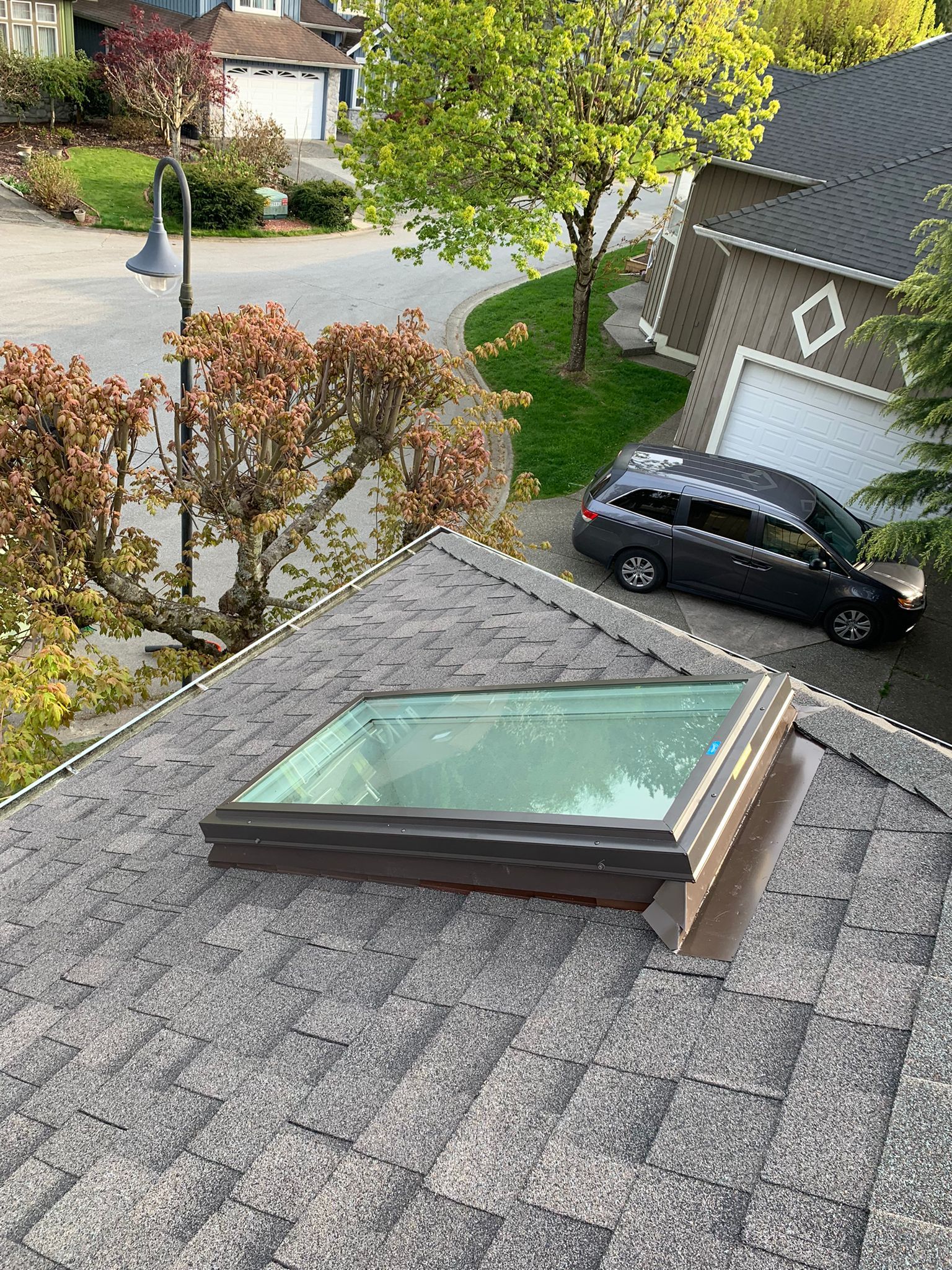 A skylight on the roof of a house with a car parked in front of it.