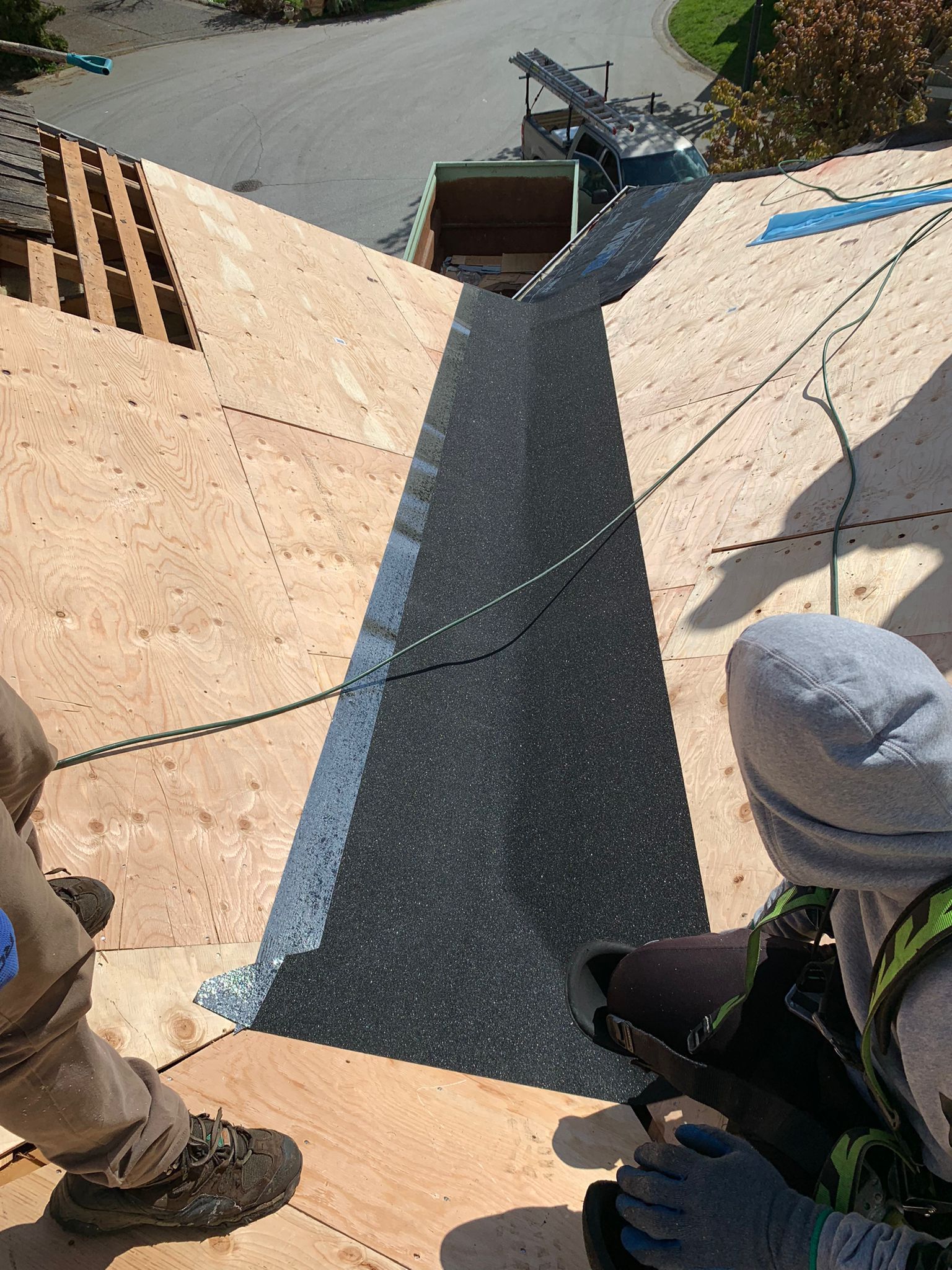 A man is cutting a piece of metal on a roof.