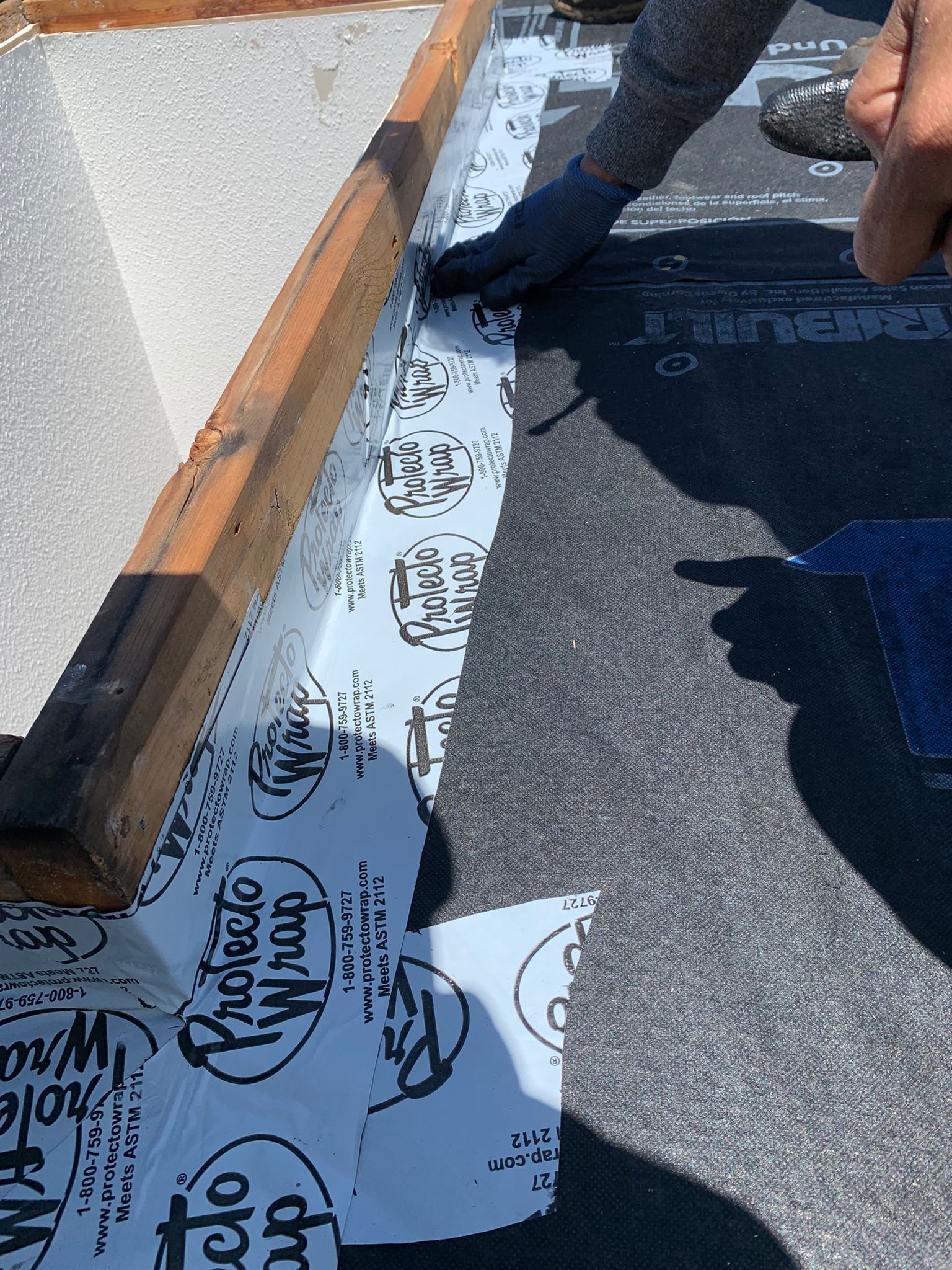 A person is cutting a piece of aluminum foil on a roof.