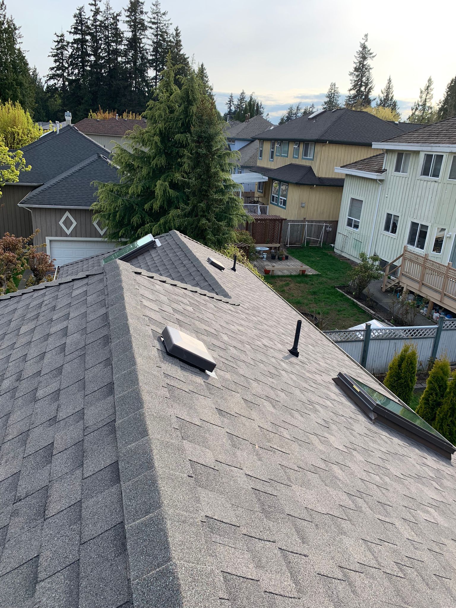 A roof with a skylight on it and a lot of houses in the background.