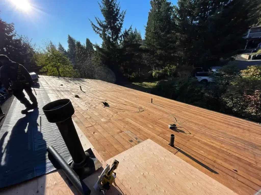 A person is working on a wooden deck with trees in the background.