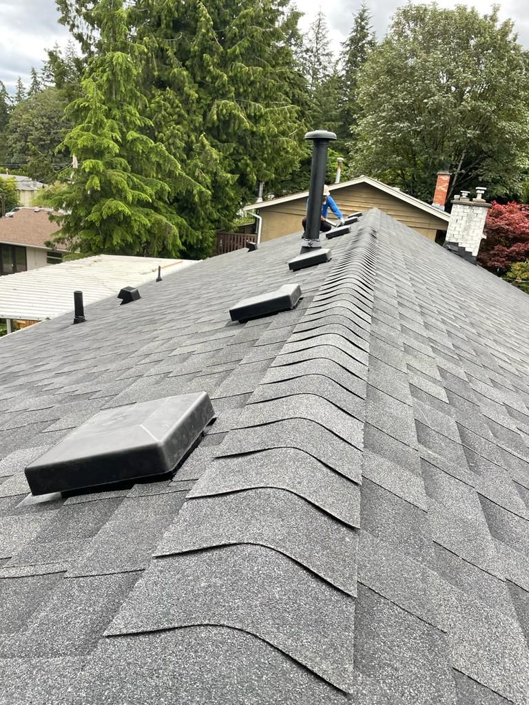 A close up of a shingle roof with a chimney on it.