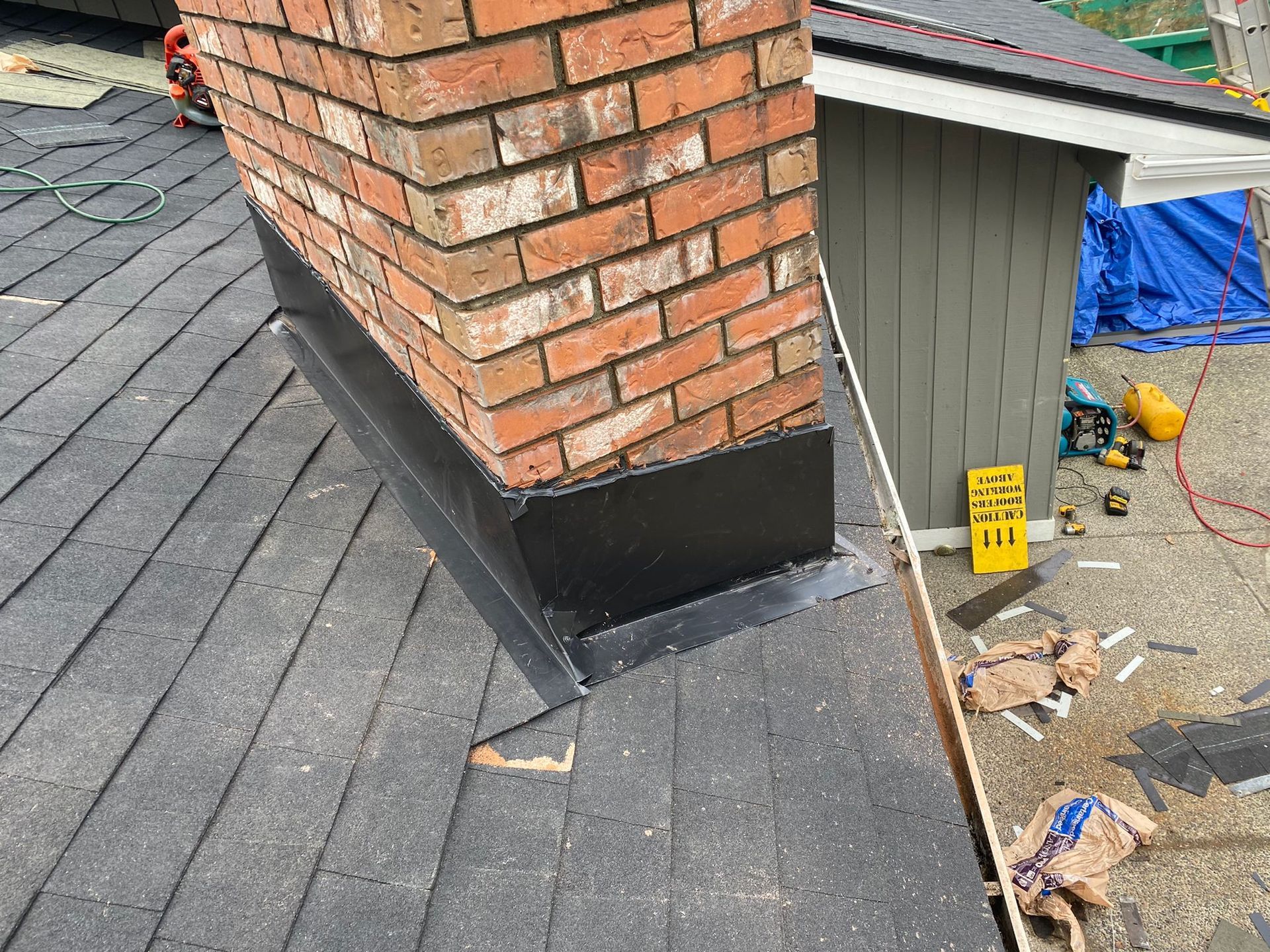 A brick chimney is sitting on top of a roof.