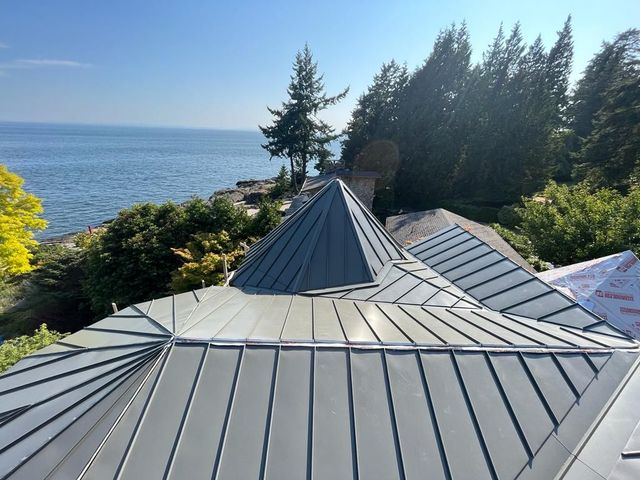 Standing seam metal roof with intersecting roof planes overlooking water