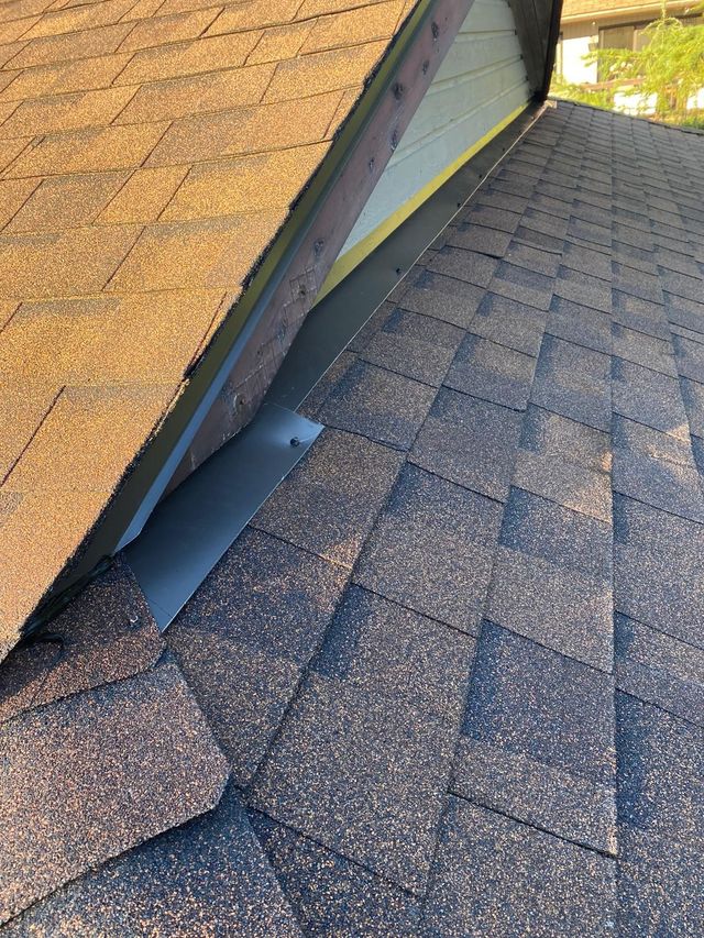 Close view of shingle roofing and metal flashing beside a wall