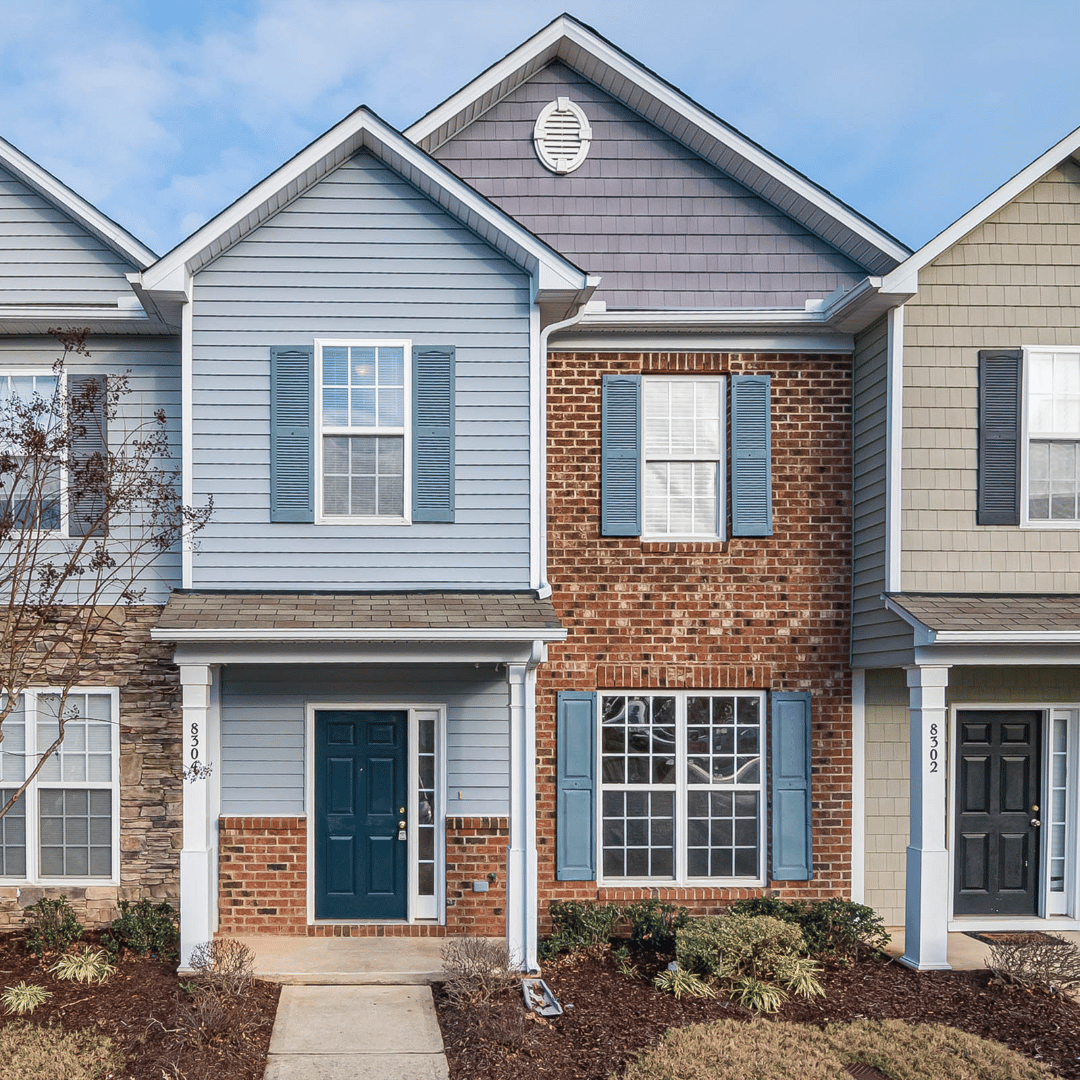 A blue and brick townhome with a dark front door, blue shutters, and a front walkway.