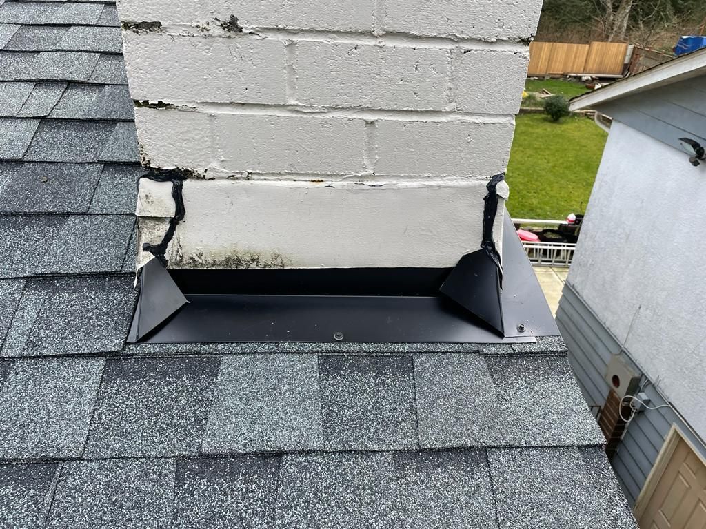 A chimney is sitting on top of a roof next to a house.