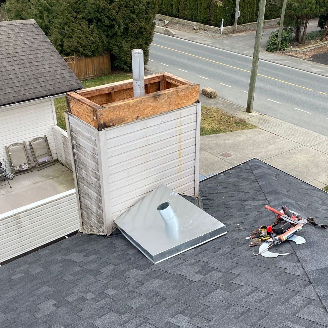 A chimney is sitting on top of a roof next to a road.