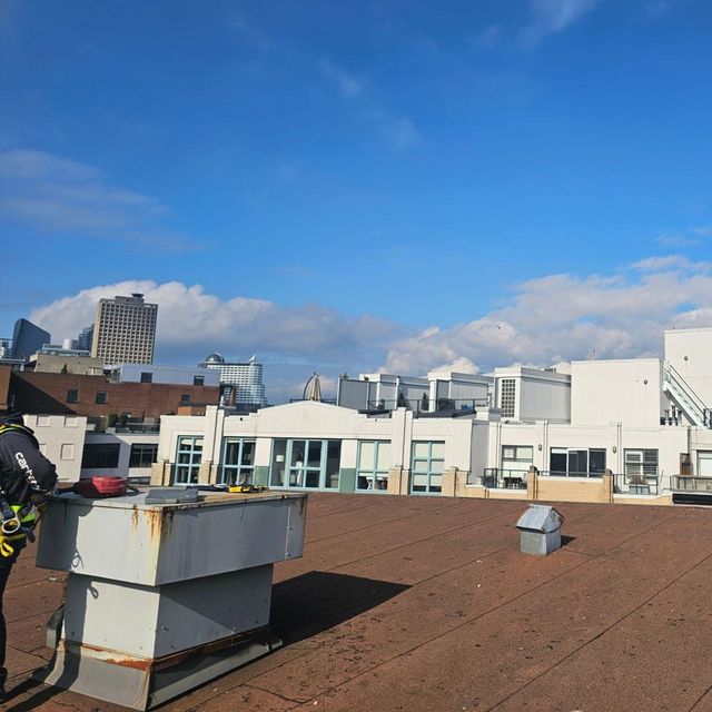 Flat roof surface with rooftop equipment, vents and buildings beyond