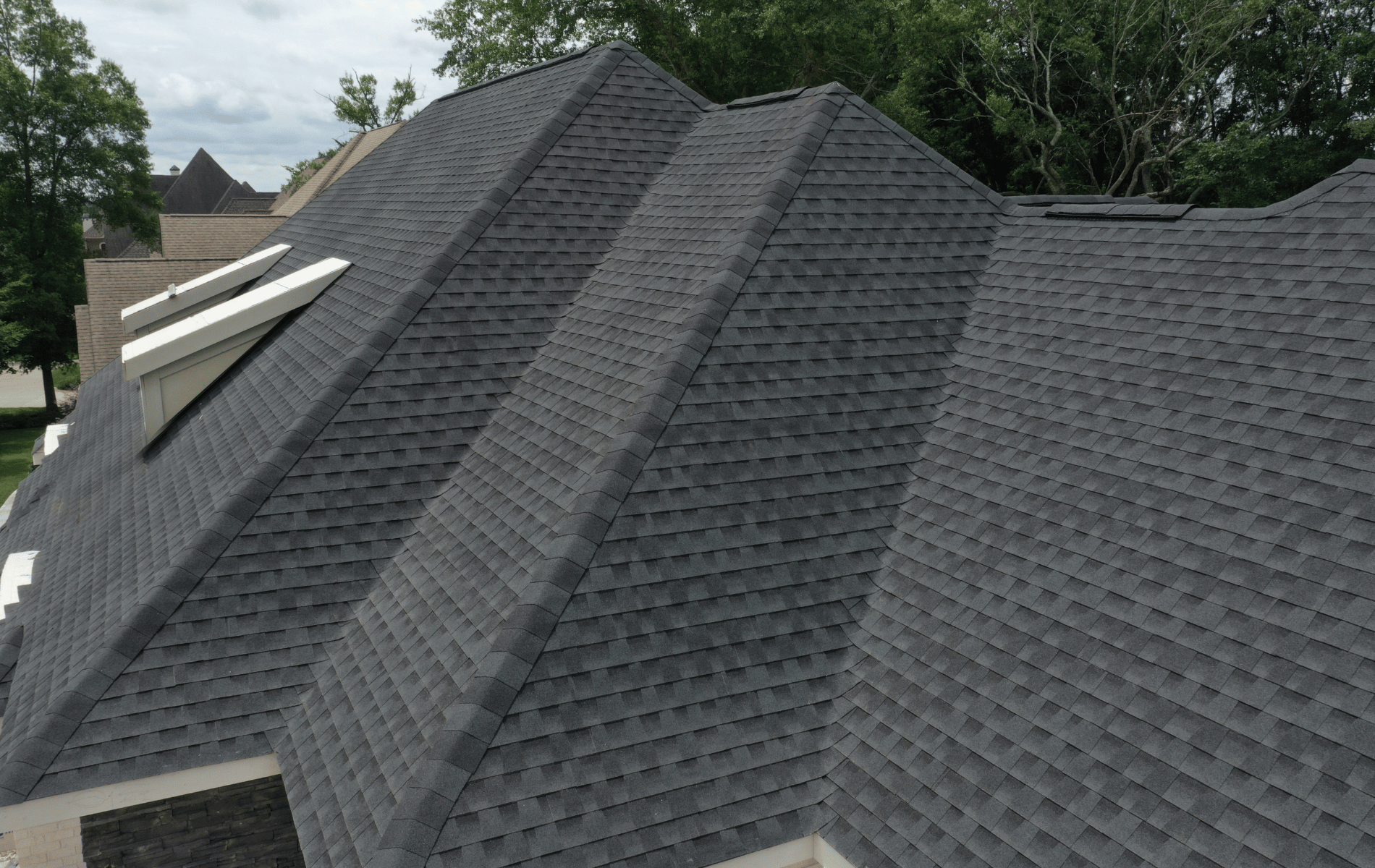 A roof with a vent on it and a building in the background.