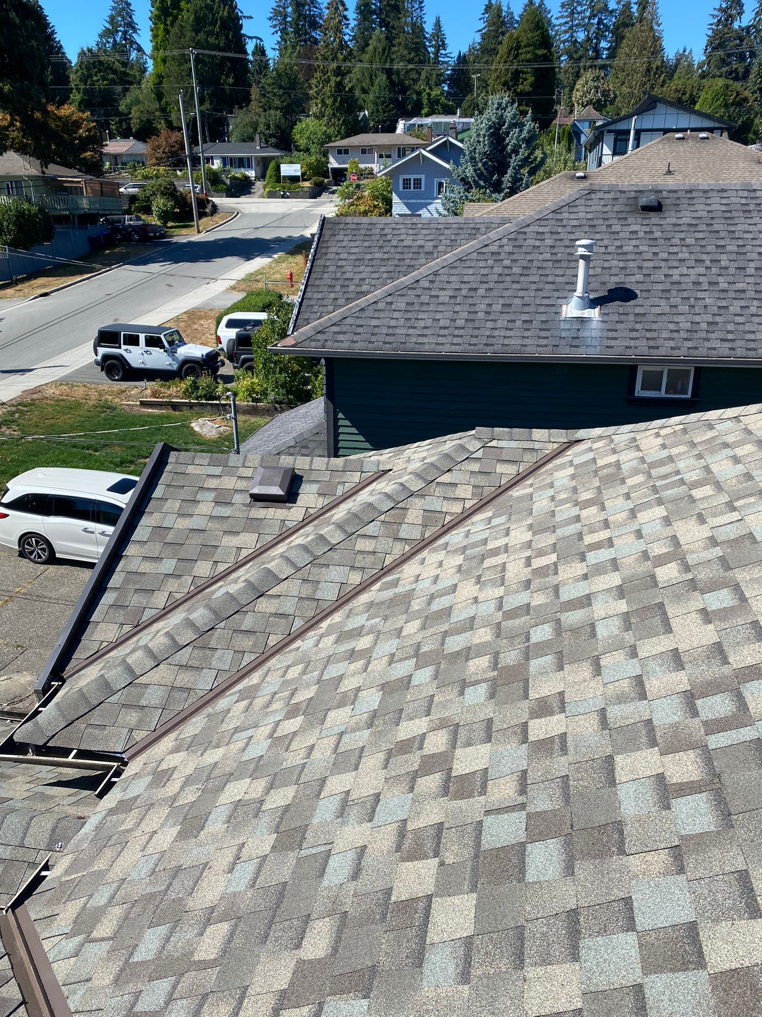 A roof with a vent on it and a building in the background.