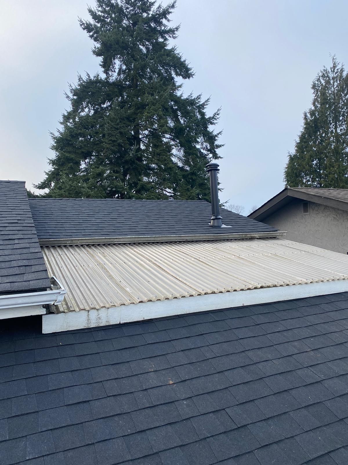 The roof of a house with a white roof and a tree in the background