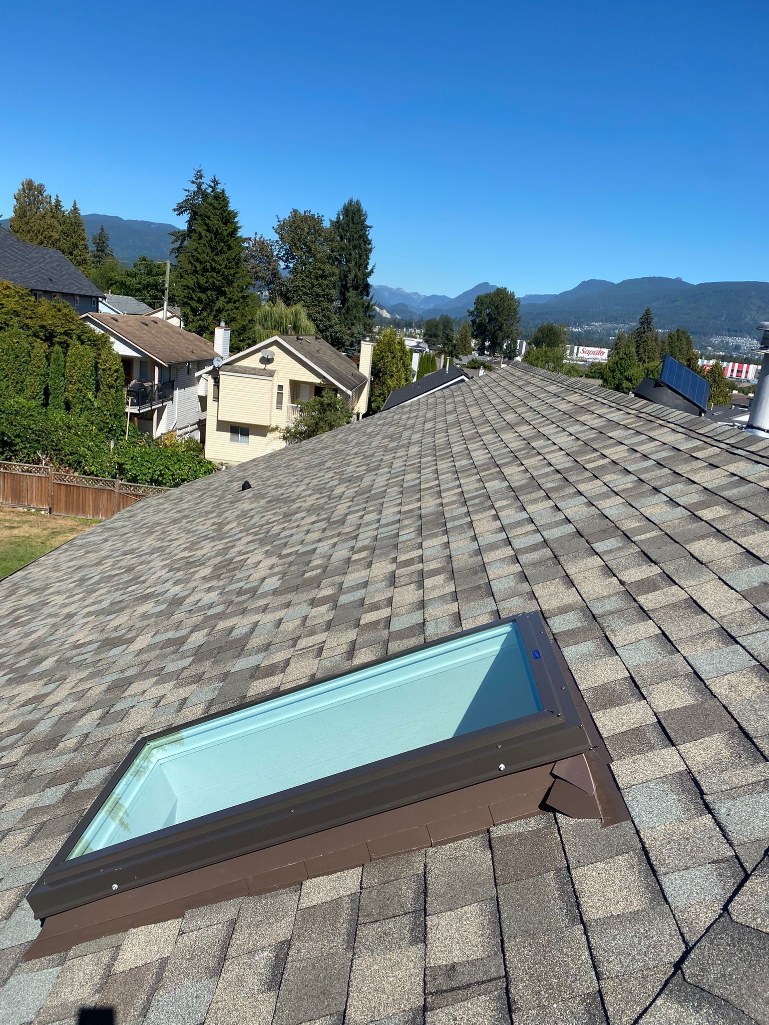 A roof with a vent on it and a building in the background.
