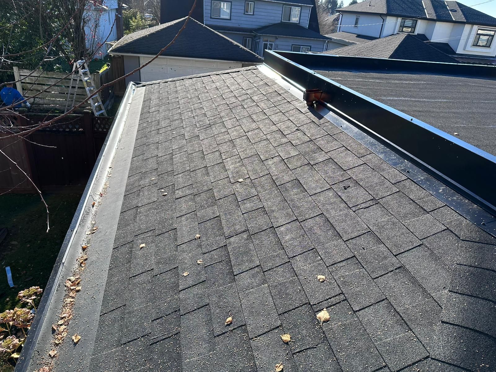 A roof with a vent on it and a building in the background.