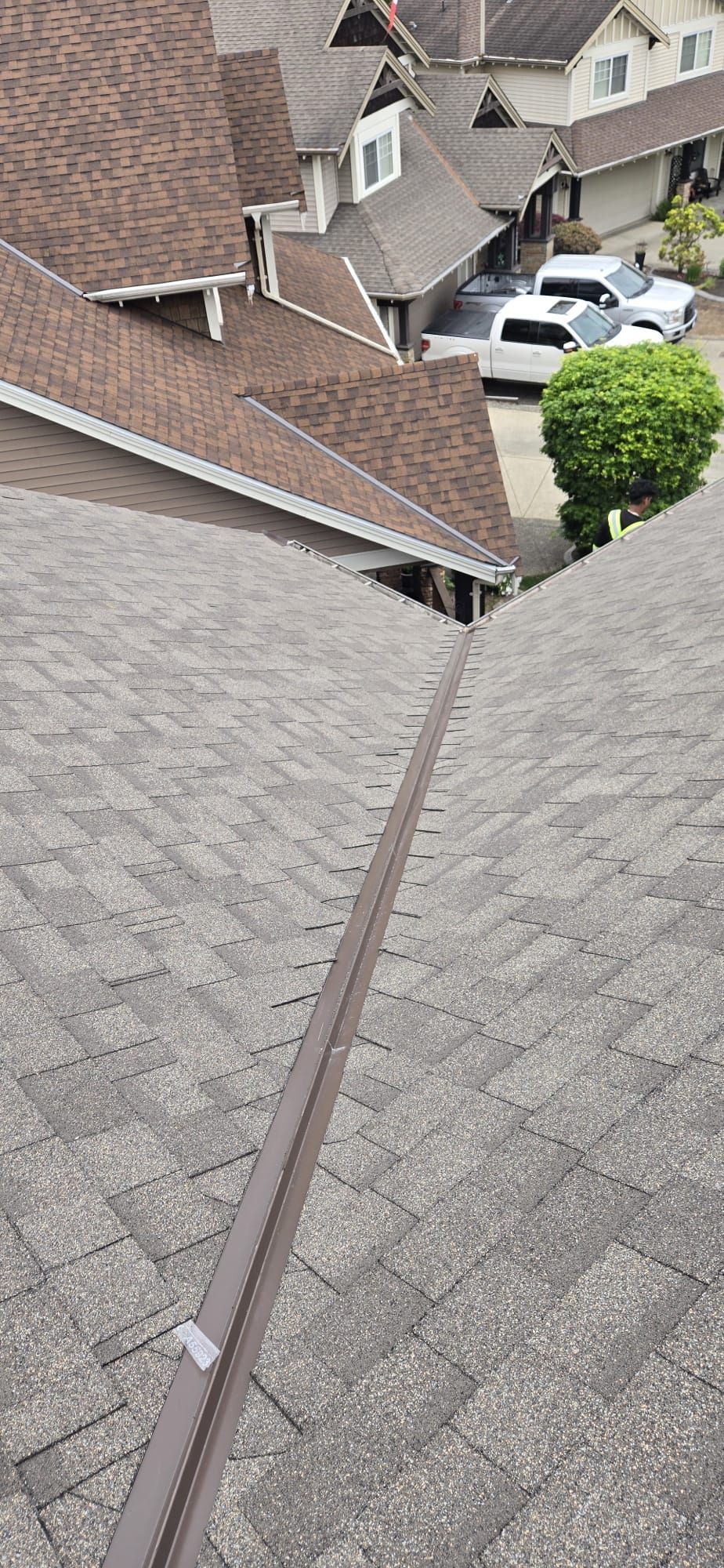 Open metal valley between two shingled planes with a Paragon crew member in hi vis below, 229 St Maple Ridge BC