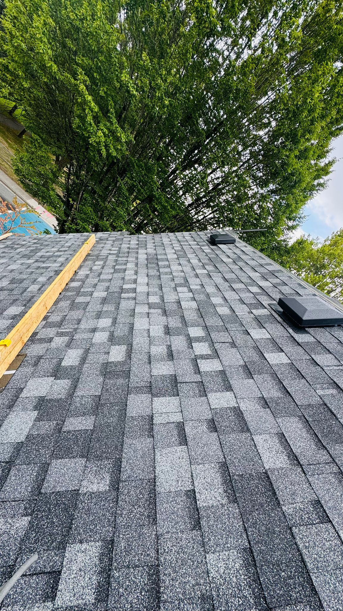 Grey shingle courses with two box vents and a temporary timber board on the slope