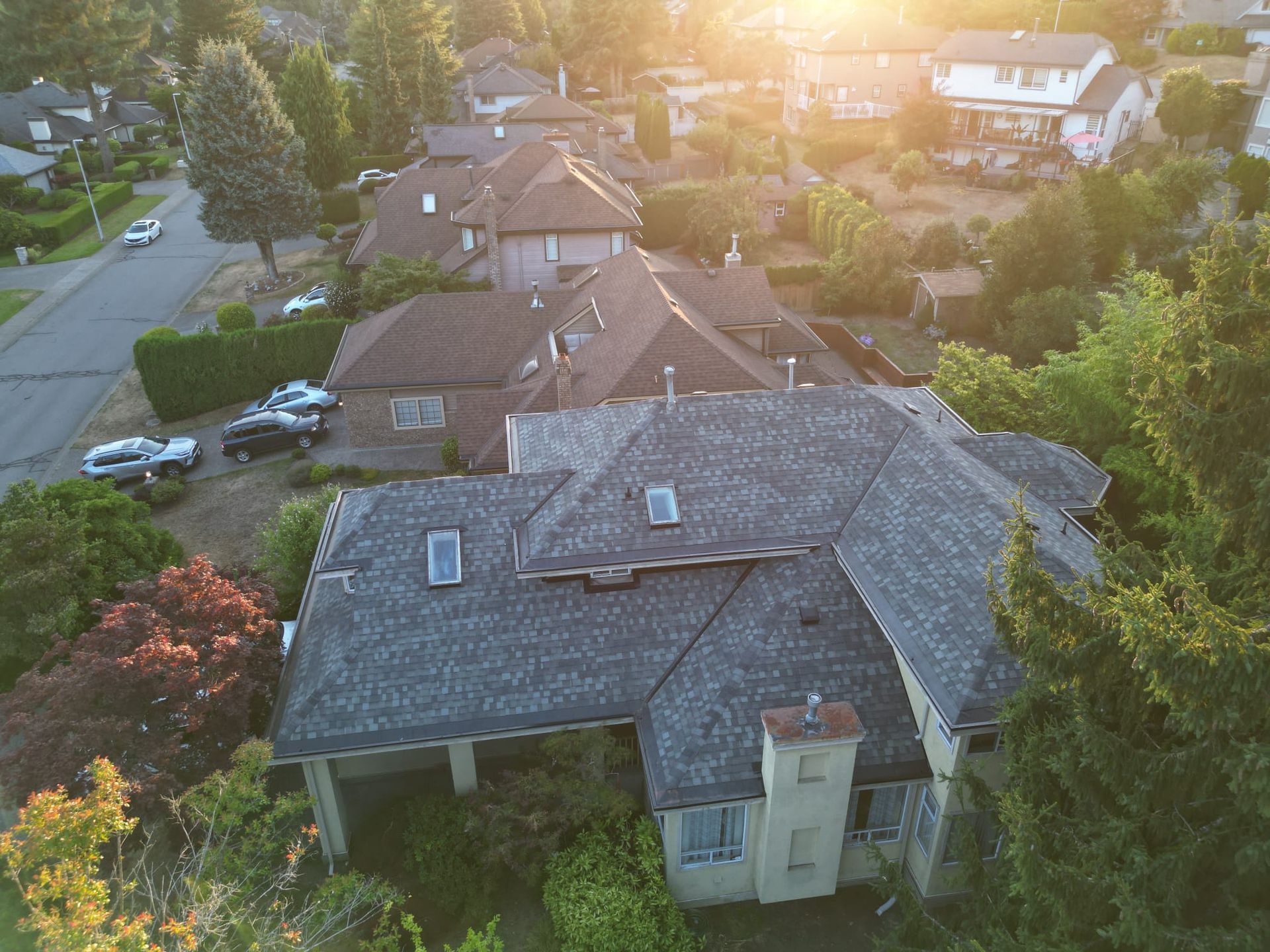 Aerial view of a shingle roof with intersecting roof planes, skylights and a chimney