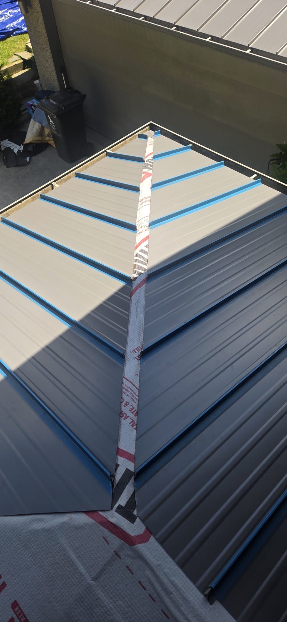 Standing seam panel ends prepared along a hip before the cap is installed