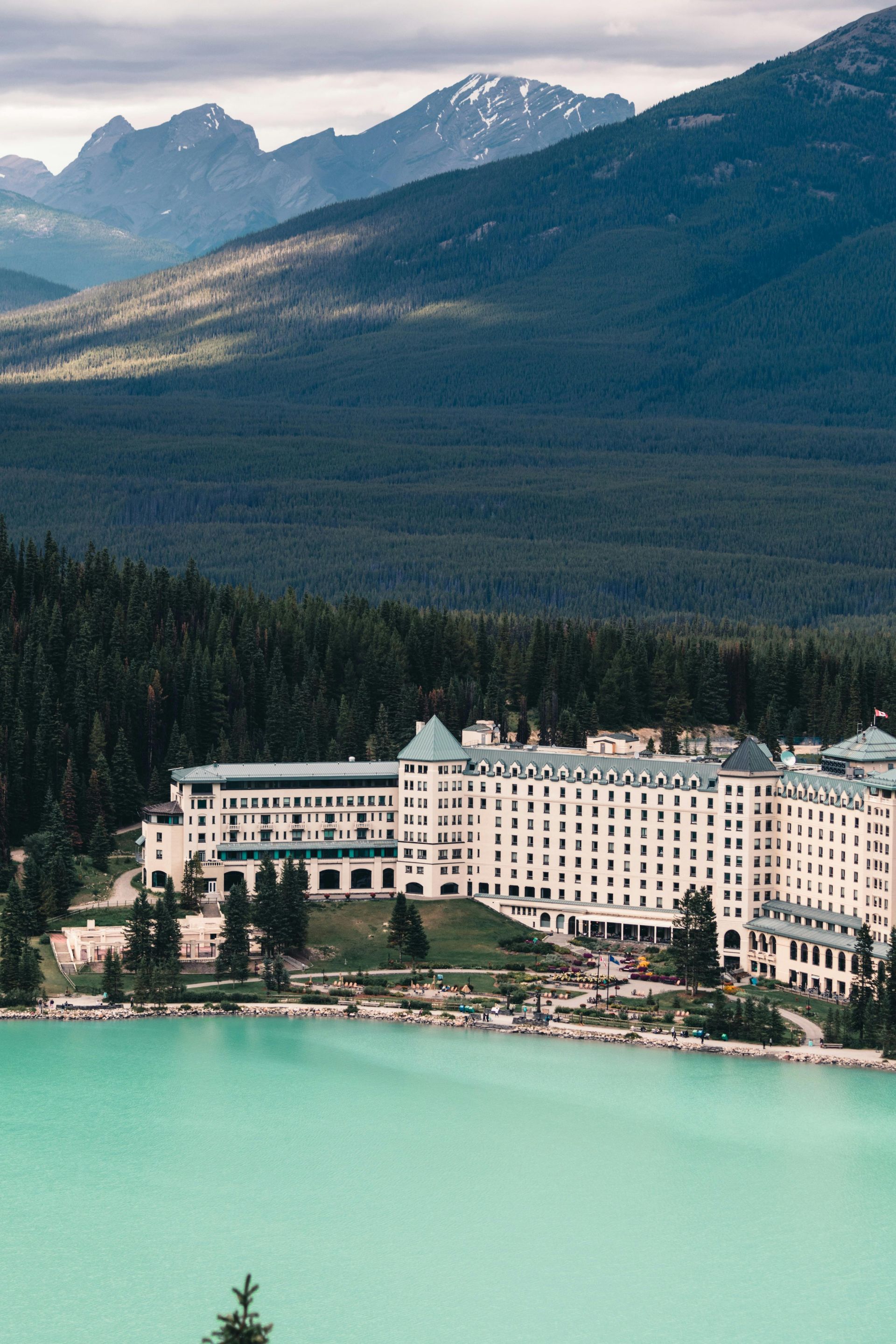 There is a large building in the middle of a lake with mountains in the background.