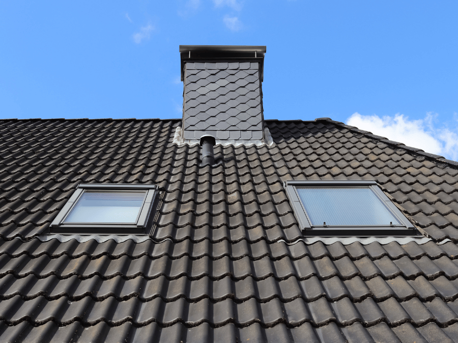 Man installing a solar panel on a house roof. Sunny day, holding panel, wearing gloves.