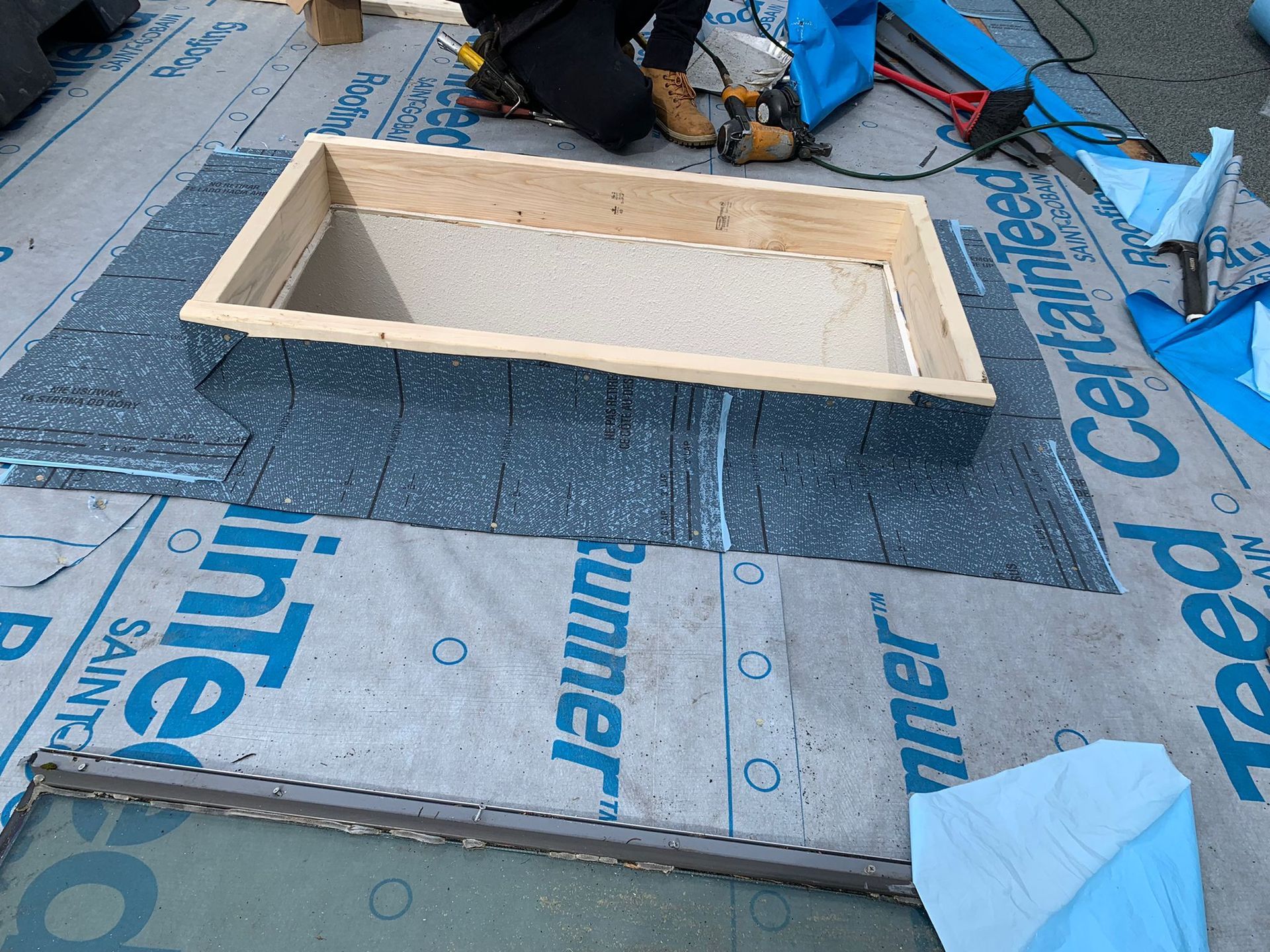A person is working on a roof with a certainteed blanket