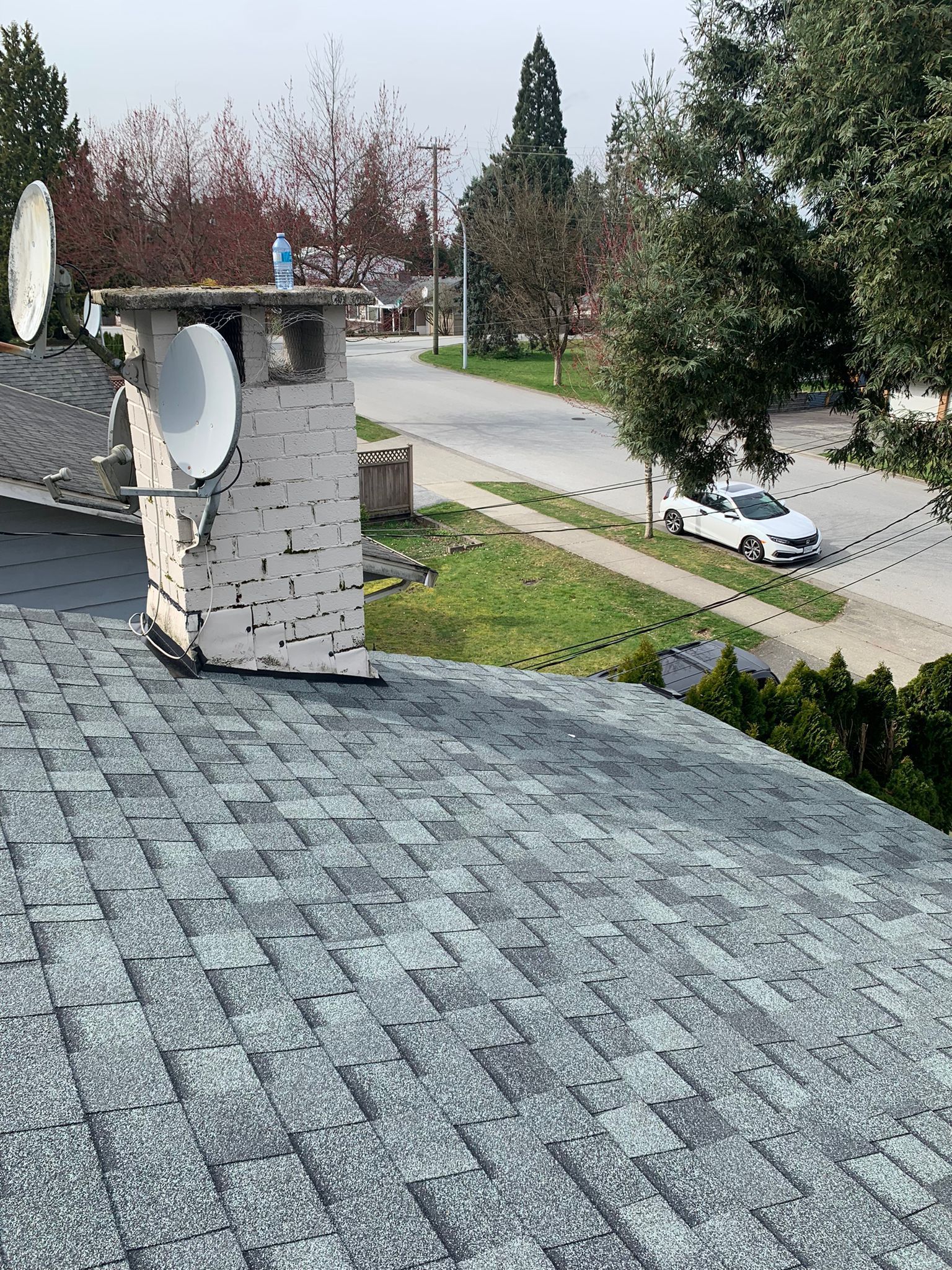 A roof with a chimney and satellite dish on it. new flashing installation completed