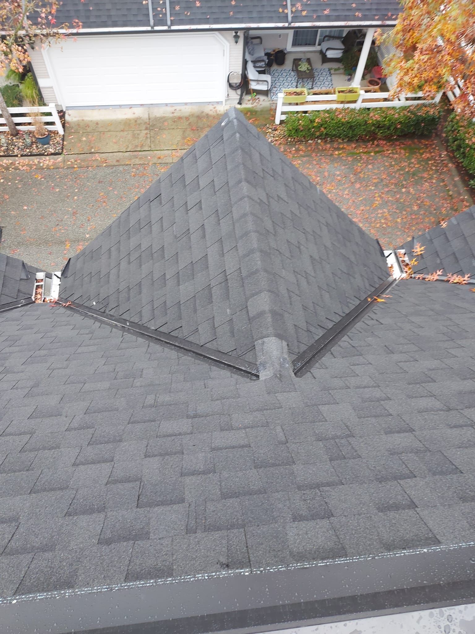 A roof with a vent on it and a building in the background.