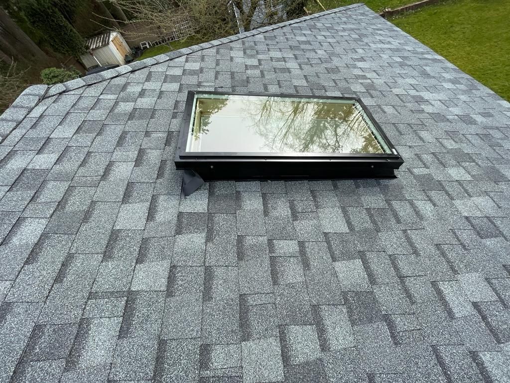 A roof with a vent on it and a building in the background.