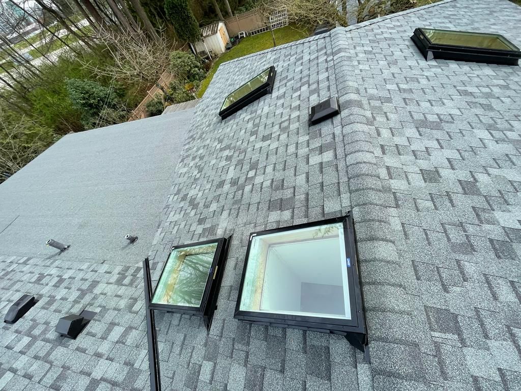 A roof with a vent on it and a building in the background.