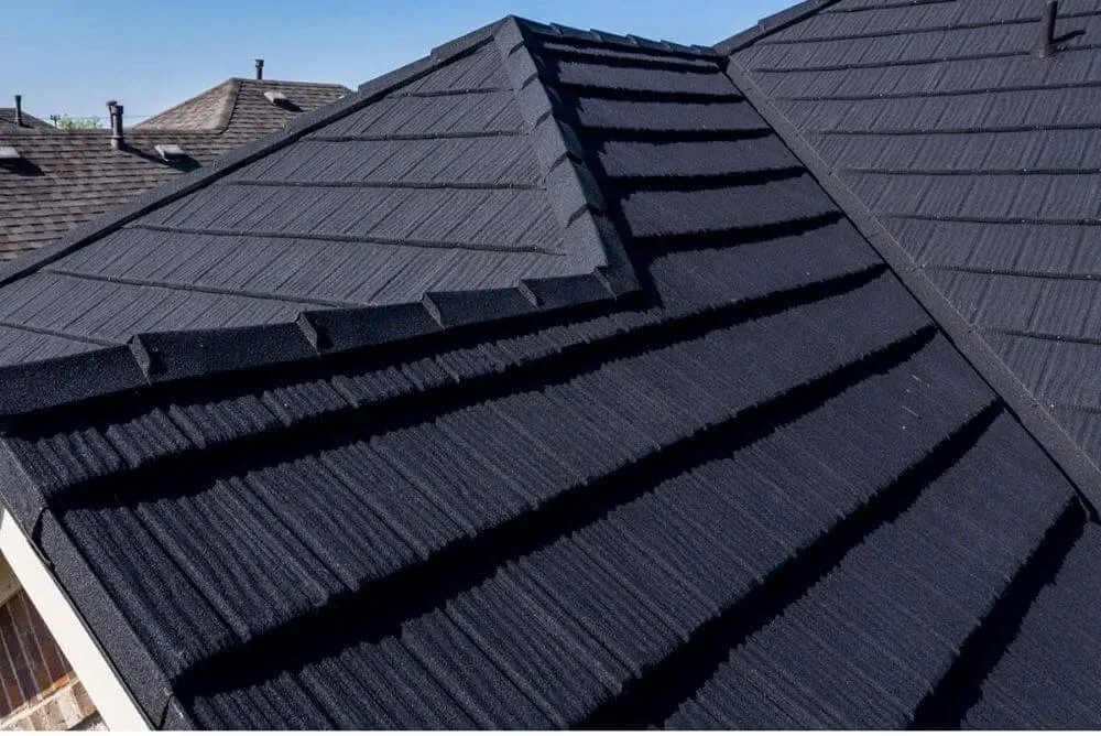 A roof with a vent on it and a building in the background.