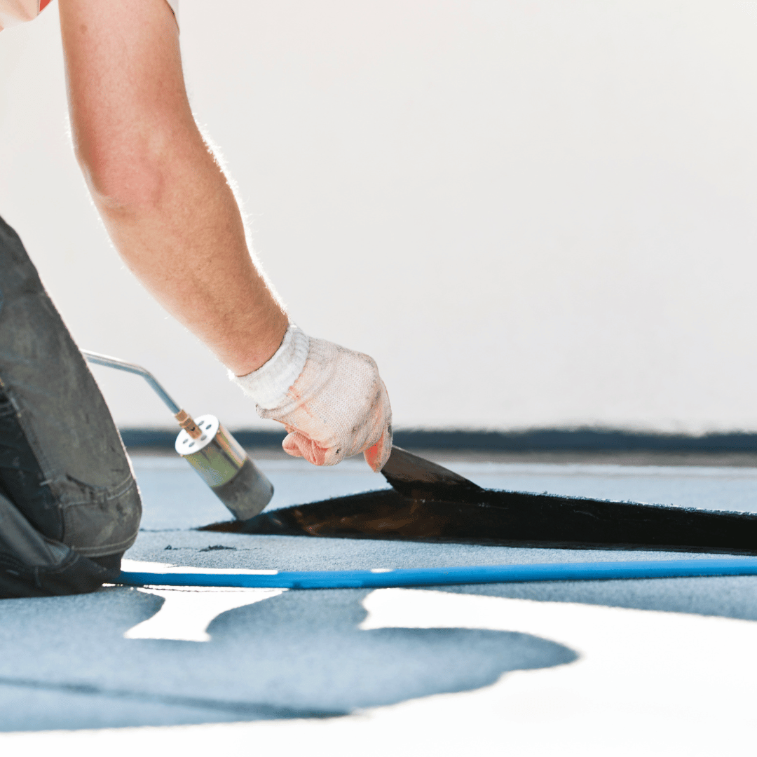 A person is using a roller on a blue floor