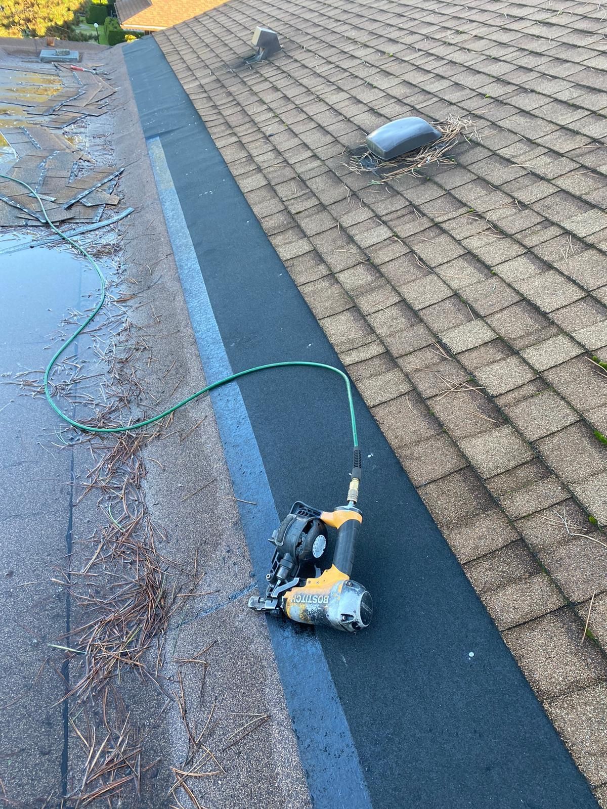 A roof with a vent on it and a building in the background.