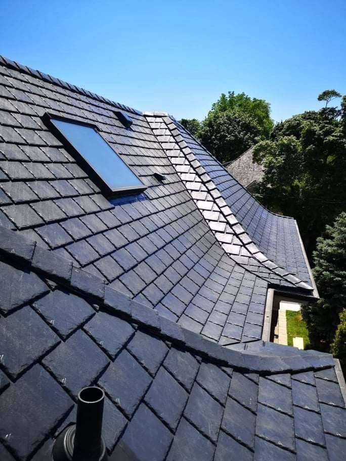 A roof with a vent on it and a building in the background.