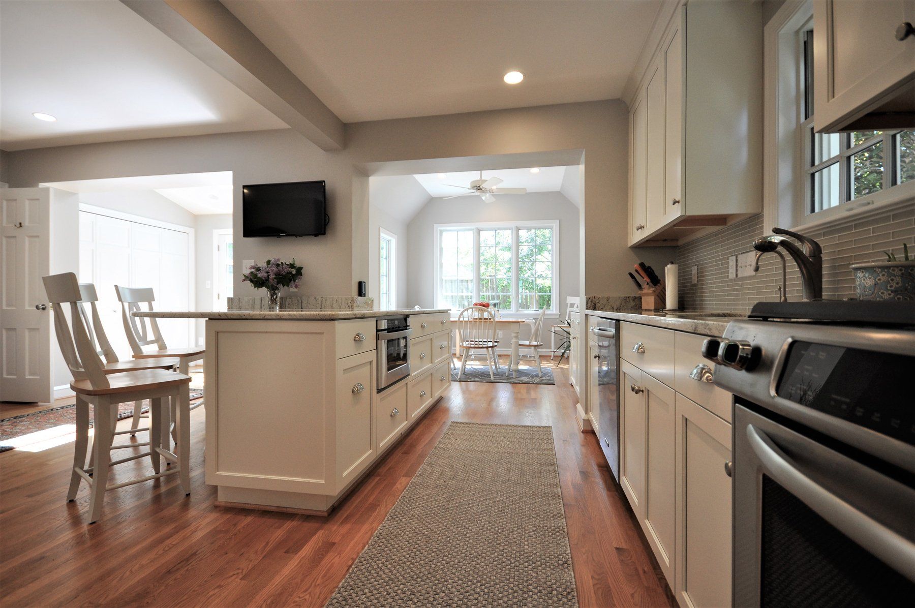 Bright kitchen with white cabinets, island, stainless appliances, and a view into a dining area in Gaithersburg