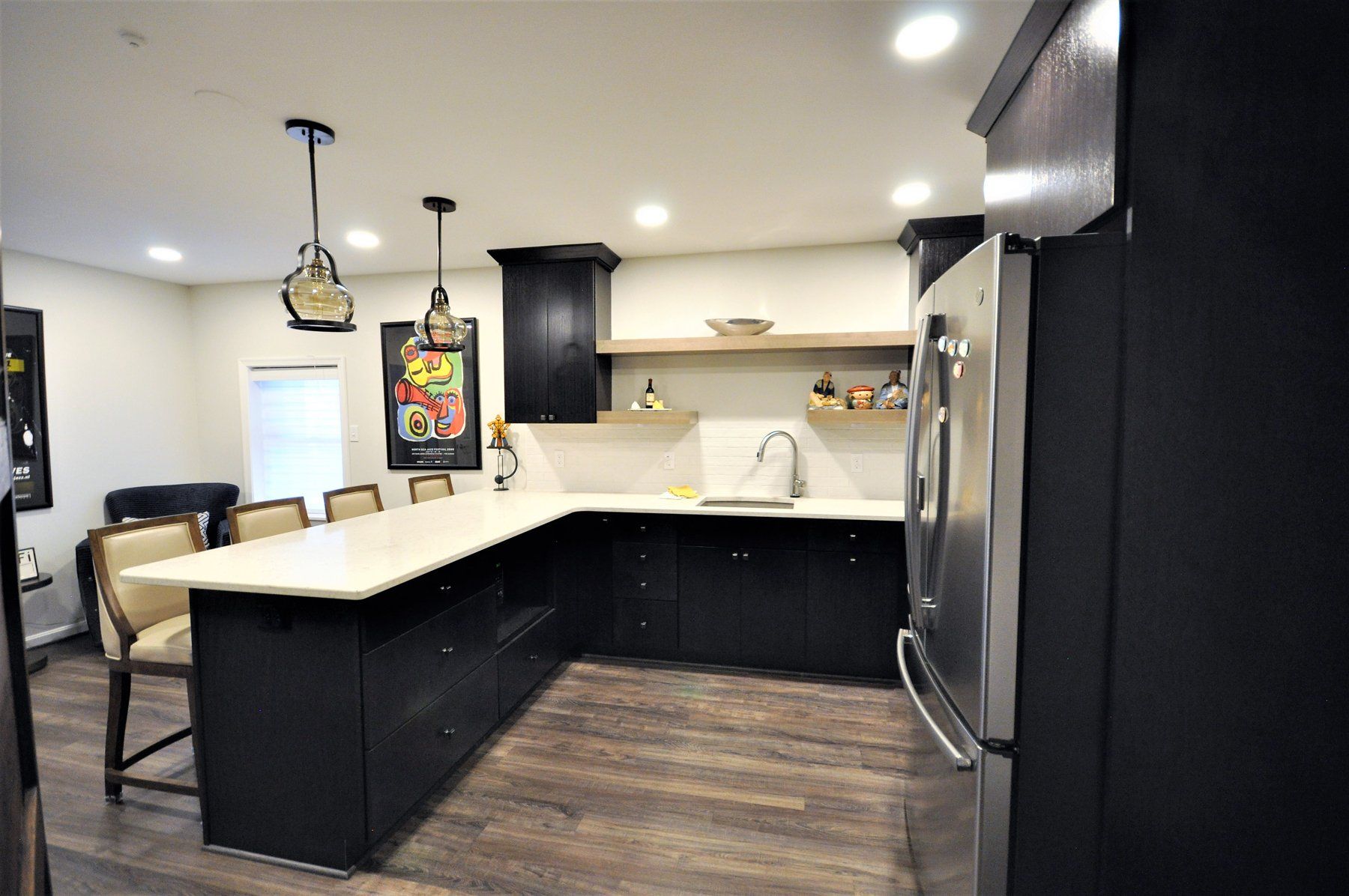 Modern kitchen with black and white cabinets, island countertop, pendant lights, and hardwood floor in Rockville