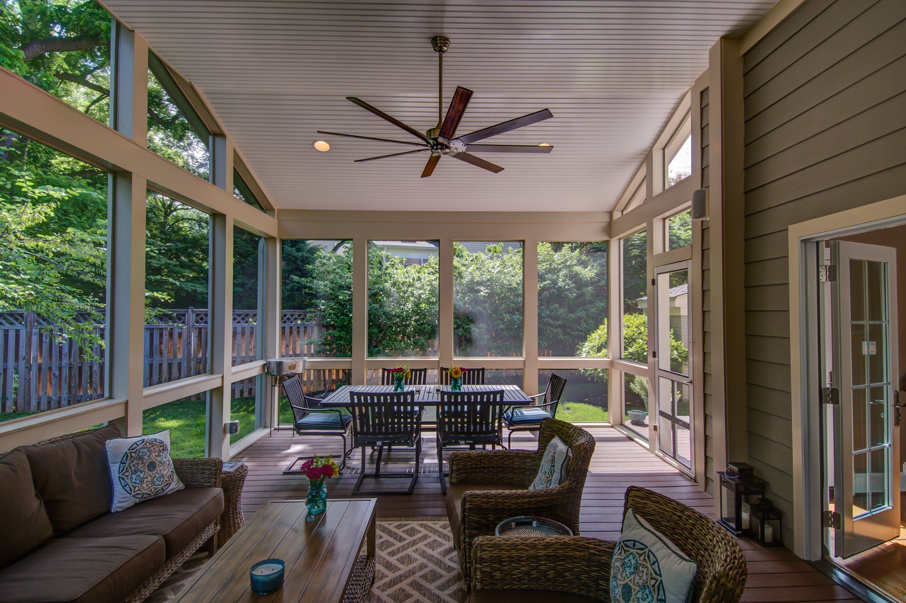Covered patio with seating, ceiling fan, and dining table overlooking a green backyard in Rockville