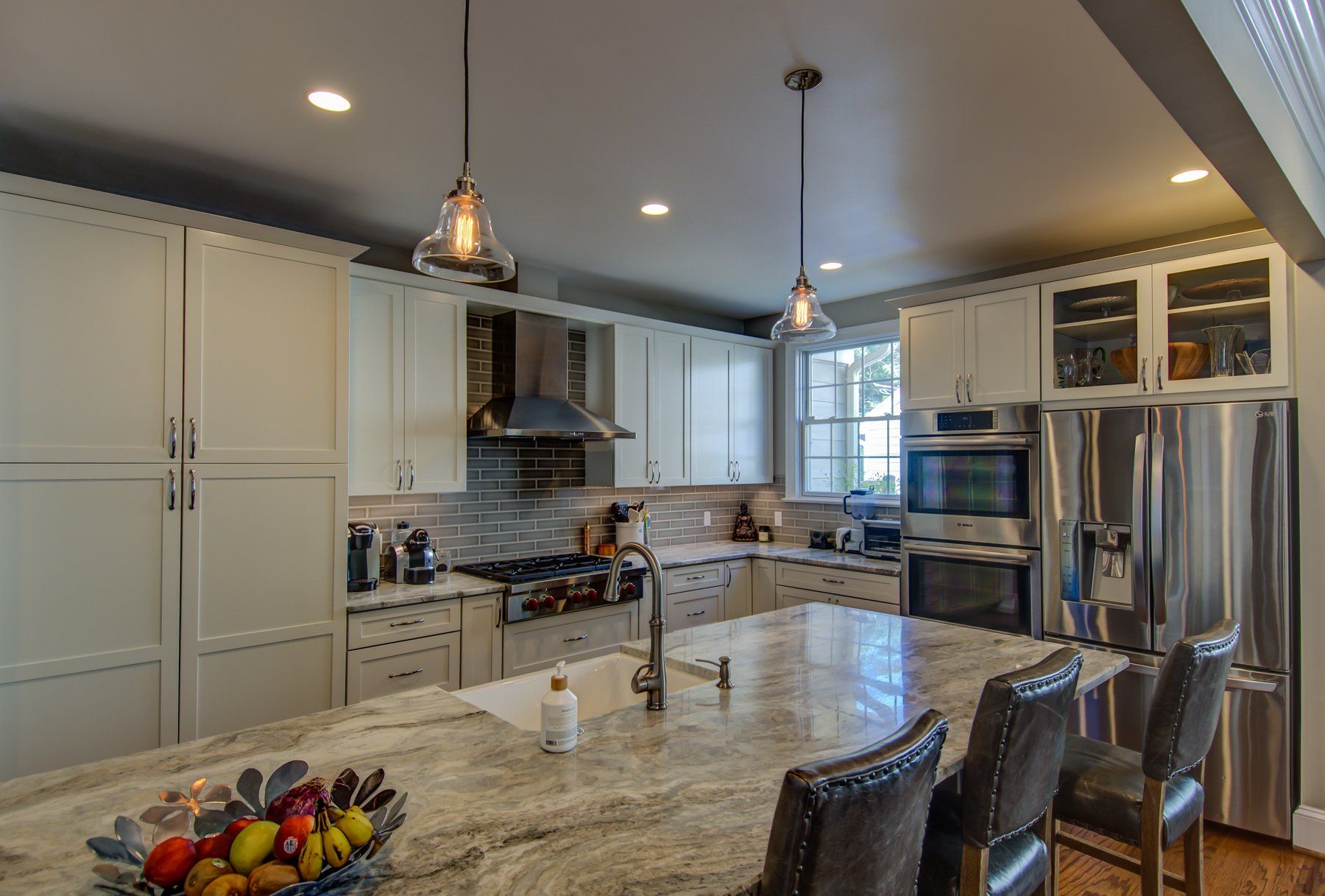 Modern kitchen with marble island, white cabinets, stainless steel appliances, and pendant lights in Rockville