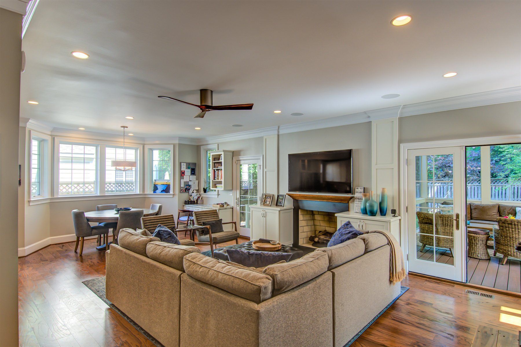 Bright open living room with tan sectional, fireplace, ceiling fan, and large windows with water views in Rockville