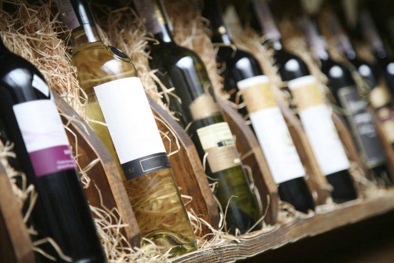 Wine bottles in straw-filled wooden crates on a shelf, each with white labels  in Rockville